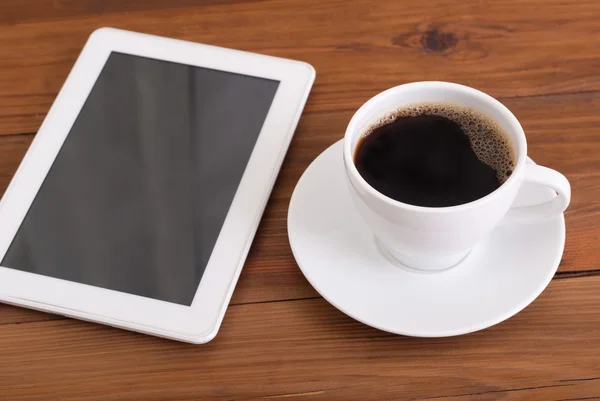 Tablet digital e xícara de café em mesa de madeira . — Fotografia de Stock
