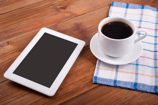 Tableta digital y taza de café en una mesa de madera . —  Fotos de Stock