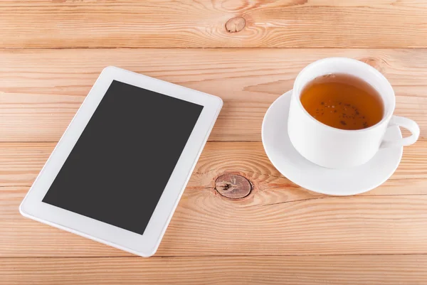 Tablet bilgisayar ve ahşap bir tabloda çay. — Stok fotoğraf