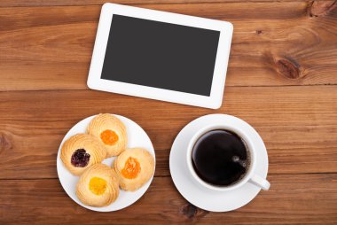 Kurabiye ve kahve Kupası dijital tablet bilgisayarda ahşap bir masa.