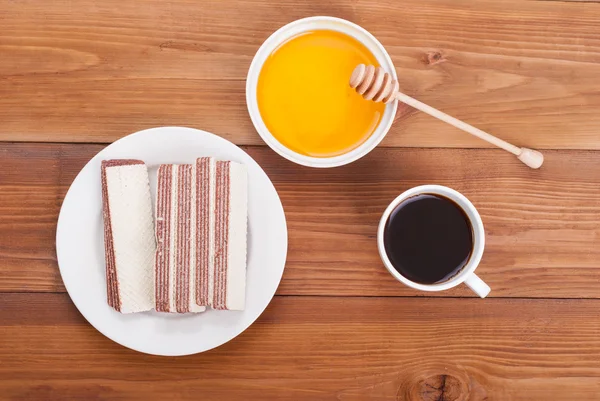 Xícara de mel de café e waffles doces em uma mesa de madeira . — Fotografia de Stock