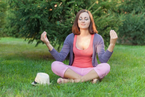 Young woman doing yoga exercises at the summer green city park. — Stock Photo, Image
