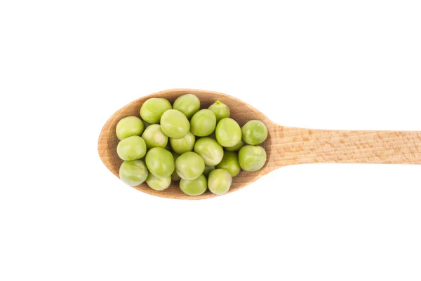 Piselli verdi in un cucchiaio di legno su sfondo bianco. — Foto Stock