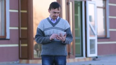 Adam ayakta bir şehir sokakta tablet bilgisayar görünüyor.