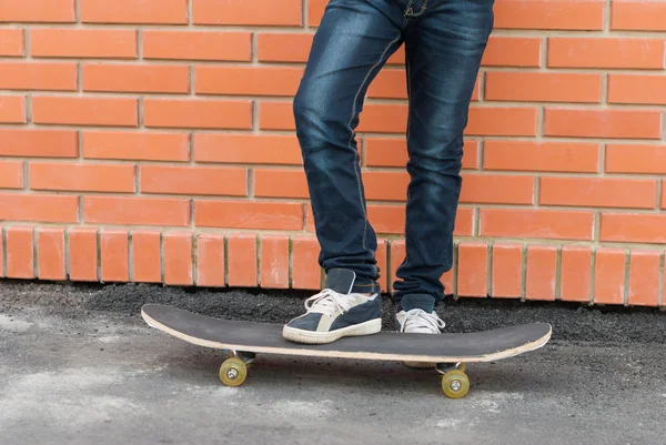 Skateboarder permanent met skateboard in de buurt van de muur. — Stockfoto