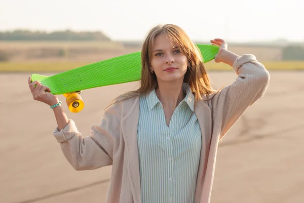 Pretty girl standing with a skateboard in the street. — Stock Photo, Image