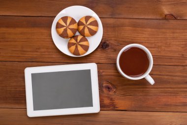 Fincan çay ve bir dijital tablet üzerinde ahşap masa tanımlama bilgileri.