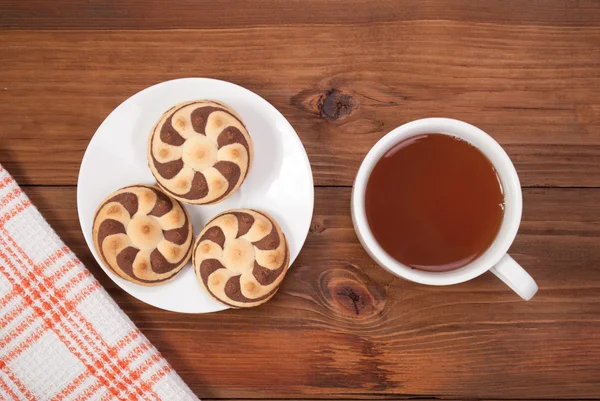 Deliciosas galletas y una taza de té sobre un fondo de madera . — Foto de Stock