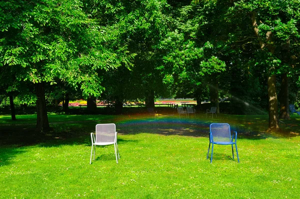 Letní park, zelený trávník, zahradní židle a automatické zavlažování — Stock fotografie