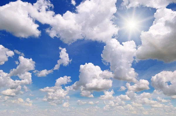 Slunce na modré obloze s bílými mraky — Stock fotografie