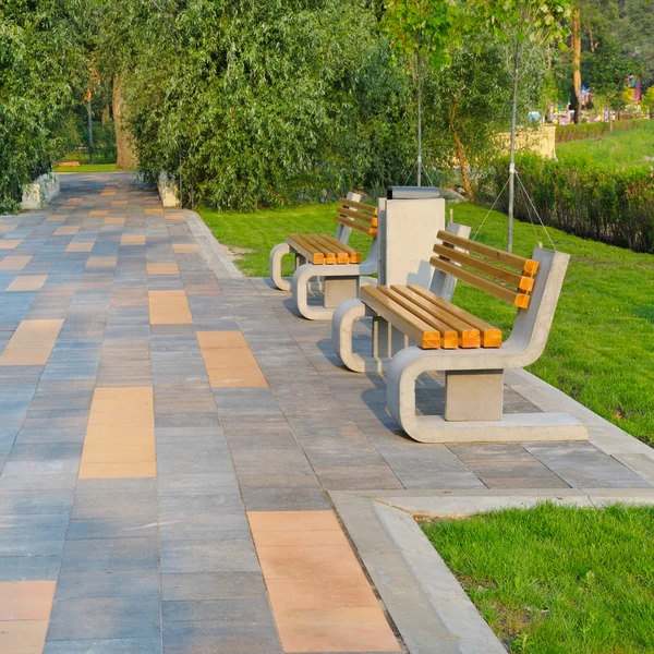 Městský park s krásnou promenádou, lavičkami a zelené trávníky — Stock fotografie