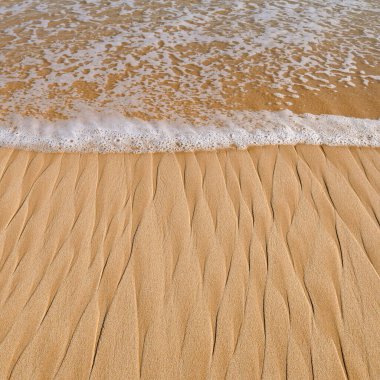 Kumlu sahilde yumuşak bir mavi okyanus dalgası. Arkaplan.