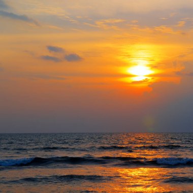 Gün batımında gökyüzü ve bulutların arasında güneş olan sakin bir deniz. Meditasyon okyanusu ve gökyüzü arka planı. Huzurlu deniz manzarası. Suyun üzerinde ufuk..