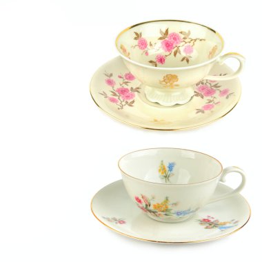 Her biri hassas bir çiçek deseni ve altın çerçeveli iki süslü porselen çay fincanı ve çay tabağı üst üste dizilmiş bir kompozisyonda sunuluyor. İzole nesneler ve beyaz arkaplan, miras, çay gibi zarif temalar için geniş bir kopya alanı sunar, 