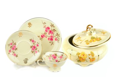 Zarif çiçek desenleri ve altın desenli güzel bir porselen koleksiyonu beyaz arka planda izole edilmiştir. Şeker kasesi, fincan ve çay tabağı içeren set, bir zarafet ve gelenek duygusunu taşıyor.