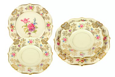 Detaylı bir çiçek deseni, istiridye kenarları ve zengin altın kaplama içeren süslü, klasik porselen plakalar koleksiyonu parlak beyaz bir arkaplanda izole edilmiştir. Zarif, yüksek anahtarlı sunum lüks, gelenek ve özel temalar için idealdir.