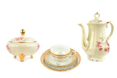 Bir şeker kasesi, istiflenmiş fincan ve fincan tabağı ve uzun bir kahve demliği de dahil olmak üzere zarif bir antika porselen çay ürünleri koleksiyonu pembe çiçekler ve altın çerçevesiyle zengince süslenmiştir. Eşyalar beyaz üzerine izole edilmiş, lüks için mükemmel bir kopya alanı yaratıyor.