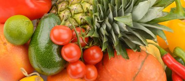 A high-angle, tight close-up showcases a rich, diverse mixture of fresh fruits and vegetables, including pineapple, avocado, tomatoes, and peppers. The vibrant colors and textures create an appealing background symbolizing healthy eating, nutrition, 