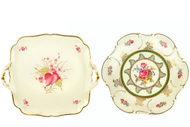 Karmaşık çiçek desenleri ve altın yaldızlı kenarlı iki zarif porselen plaka beyaz üzerinde izole edilmiştir. Bu dekoratif antika tabaklar lüks yemek ve ev dekorasyonu için ideal..