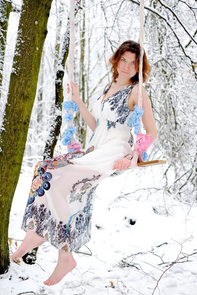 Flickan på svingen i skogen vinter — Stockfoto
