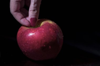 Genç bir kadın siyah arka planda bir elma tutuyor, yakın plan, izole edilmiş.