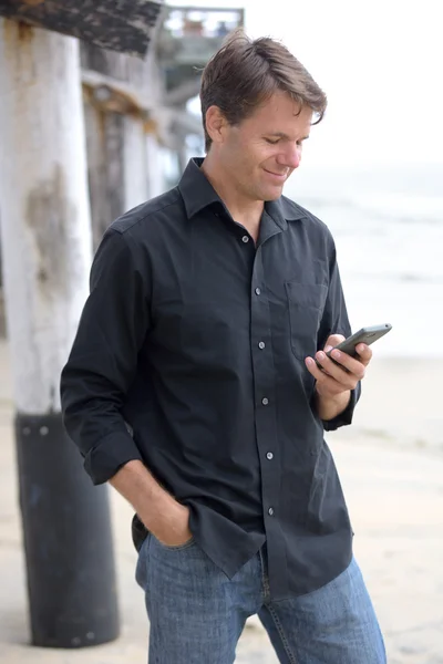 El hombre se comunica con el teléfono inteligente en la playa — Foto de Stock