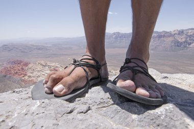 Rugged feet in primitive sandals on mountain