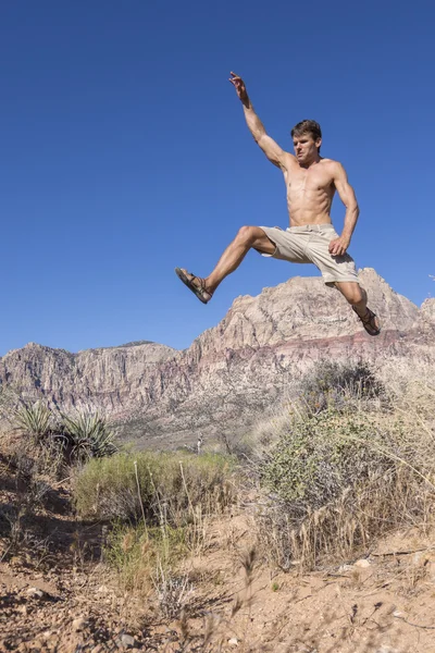 Running man jumping high over bushes in desert — Stock Photo, Image