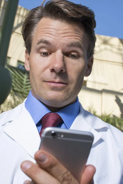 Lekarz przeglądając wiadomości inteligentny telefon — Zdjęcie stockowe