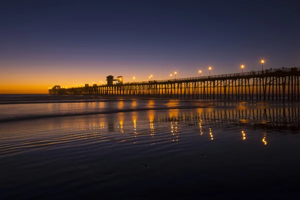 Pôr-do-sol brilhante praia com cais — Fotografia de Stock