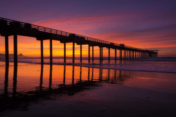 Muelle de silueta en la playa y puesta de sol brillante — Foto de Stock