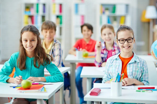 Pupils sitting by desks — Stock Photo, Image