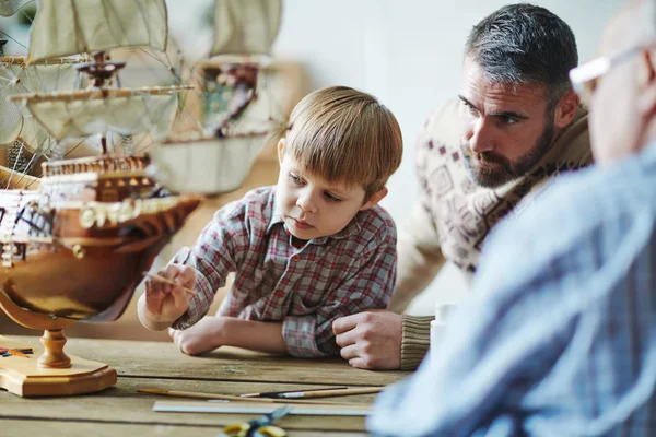 Boy painting toy ship — Stock Photo, Image