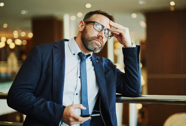 Nadenkend werknemer met cellphone — Stockfoto