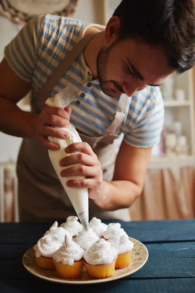 Homem que decora muffins — Fotografia de Stock