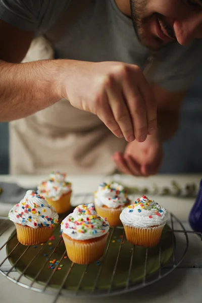 Homem que decora muffins — Fotografia de Stock