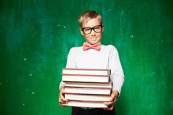 Clever schoolboy with stack of books — Stock Photo, Image