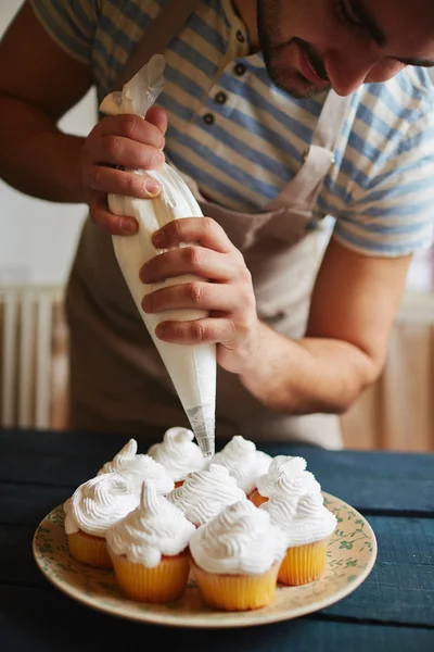 Homem que decora muffins — Fotografia de Stock
