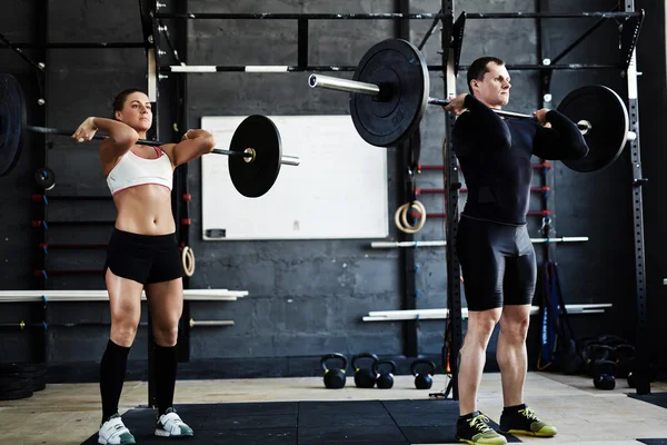 Muž a žena barbells zvedání — Stock fotografie