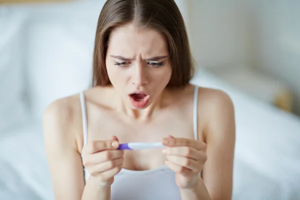 Шокированная женщина с тестом на беременность — стоковое фото