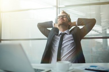 Elleri başının arkasında olan bir iş adamı