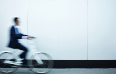 İşadamı duvarı boyunca hareketli bisiklet üzerinde