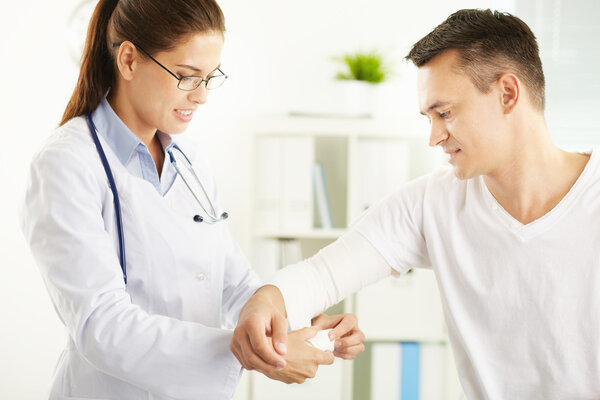 Woman doctor bandaging hand