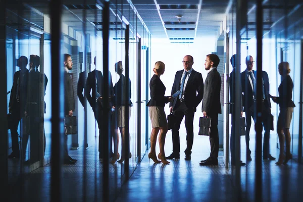 Trois employés de bureau parlent dans le couloir — Photo