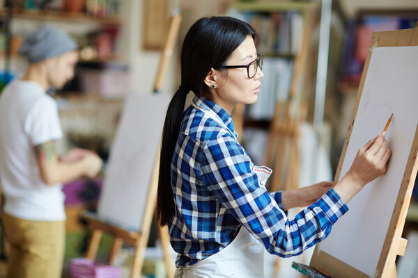 Asian artist drawing sketch on easel