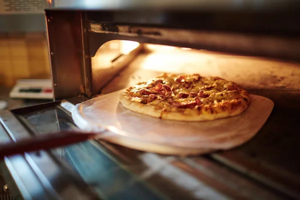 Gebakken pizza worden genomen uit — Stockfoto