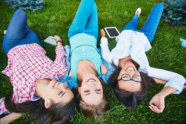 Meninas alegres relaxando na grama — Fotografia de Stock