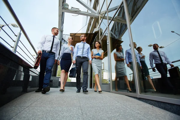 Colleagues moving along glass wall — Stock Photo, Image