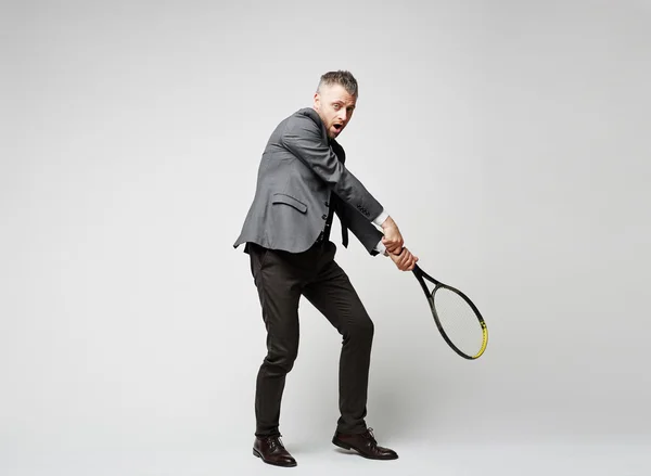 Бизнесмен держит теннисную ракетку — стоковое фото