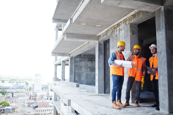 Grupp av instruktörer pratar på byggarbetsplats — Stockfoto